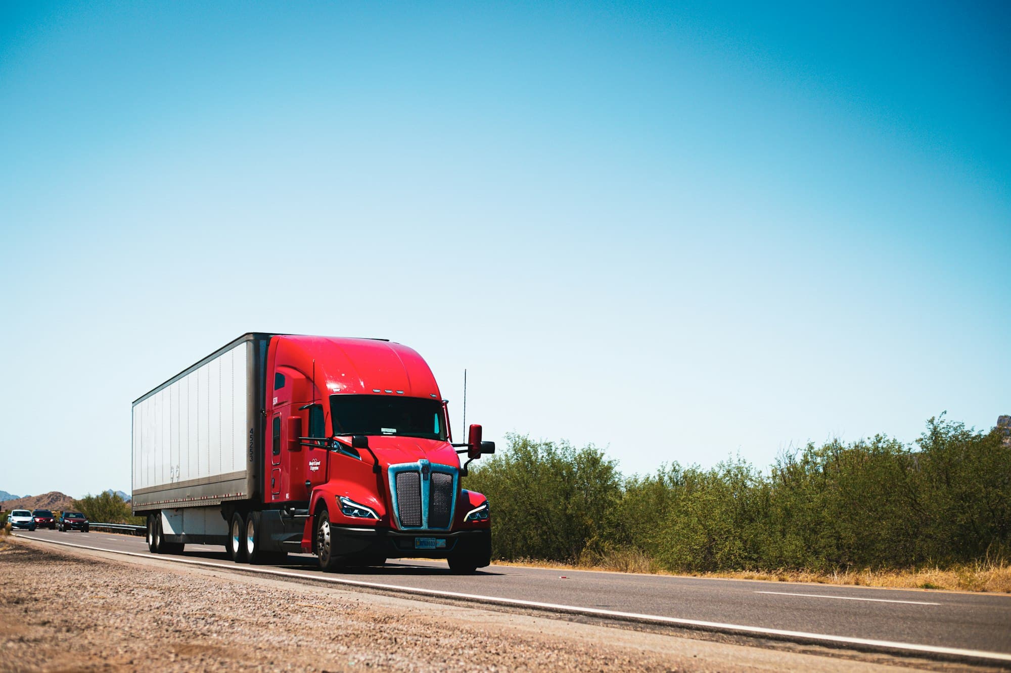 Красный тягач Kenworth с прицепом dry van на шоссе в Аризоне